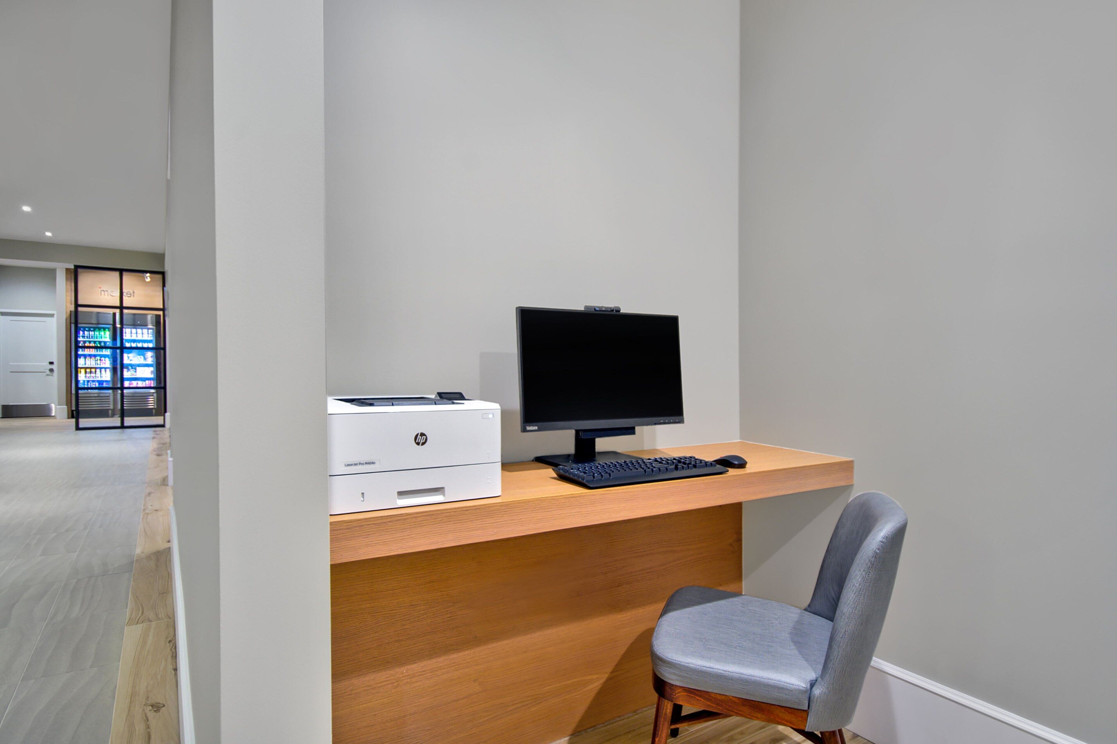 A modern office space with a wooden desk, a computer, and a printer.