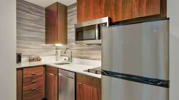 Una cocina moderna con armarios de madera, un refrigerador de acero inoxidable, un microondas y un lavamanos.
