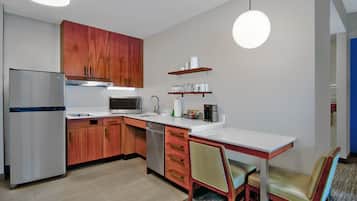 Een moderne keuken met houten kastjes, roestvrijstalen apparatuur, een wit aanrecht en een eethoek met een tafel en stoelen.