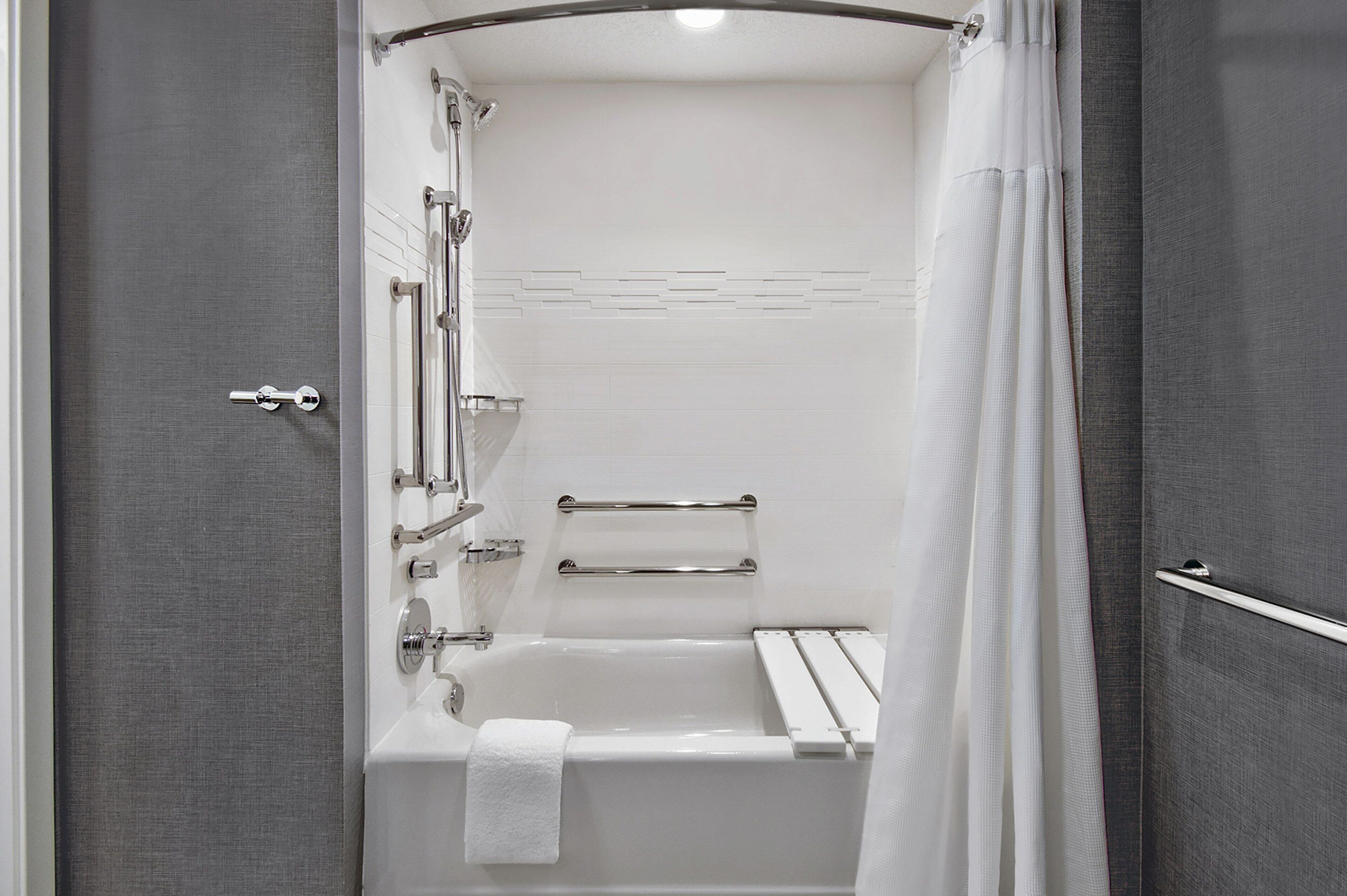 A modern bathroom with a bathtub, shower, and towel rack.