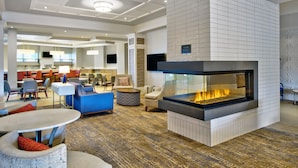 Un hall modern amb una llar de foc gran, seients confortables i un sostre ben il·luminat.