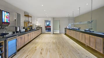 A modern kitchen with wooden cabinets, stainless steel appliances, and a digital menu display.