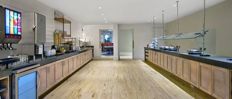 A modern kitchen with wooden cabinets, stainless steel appliances, and a digital menu display.
