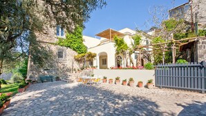 Un cortile con pavimentazione in pietra, sedute all'aperto, piante in vaso e un pergolato in legno.