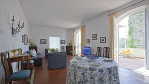 Un soggiorno spazioso con zona pranzo, divano, TV e balcone con vista.