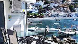 Un balcón con mesa y sillas que da a una ciudad costera con barcos y edificios.