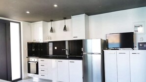 Una cocina moderna con armarios blancos, electrodomésticos de acero inoxidable e iluminación colgante.