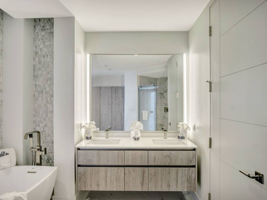 A modern bathroom with a double sink vanity, a large mirror, and a freestanding bathtub.