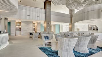 A spacious lobby with high ceilings, modern seating, and a central staircase.