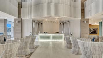 A reception area with a modern design, featuring a central counter, seating area with wicker chairs, and a unique ceiling structure.