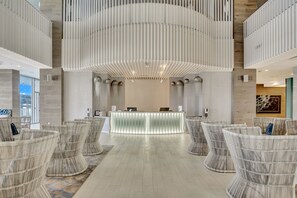 A reception area with a modern design, featuring a central counter, seating area with wicker chairs, and a unique ceiling structure.