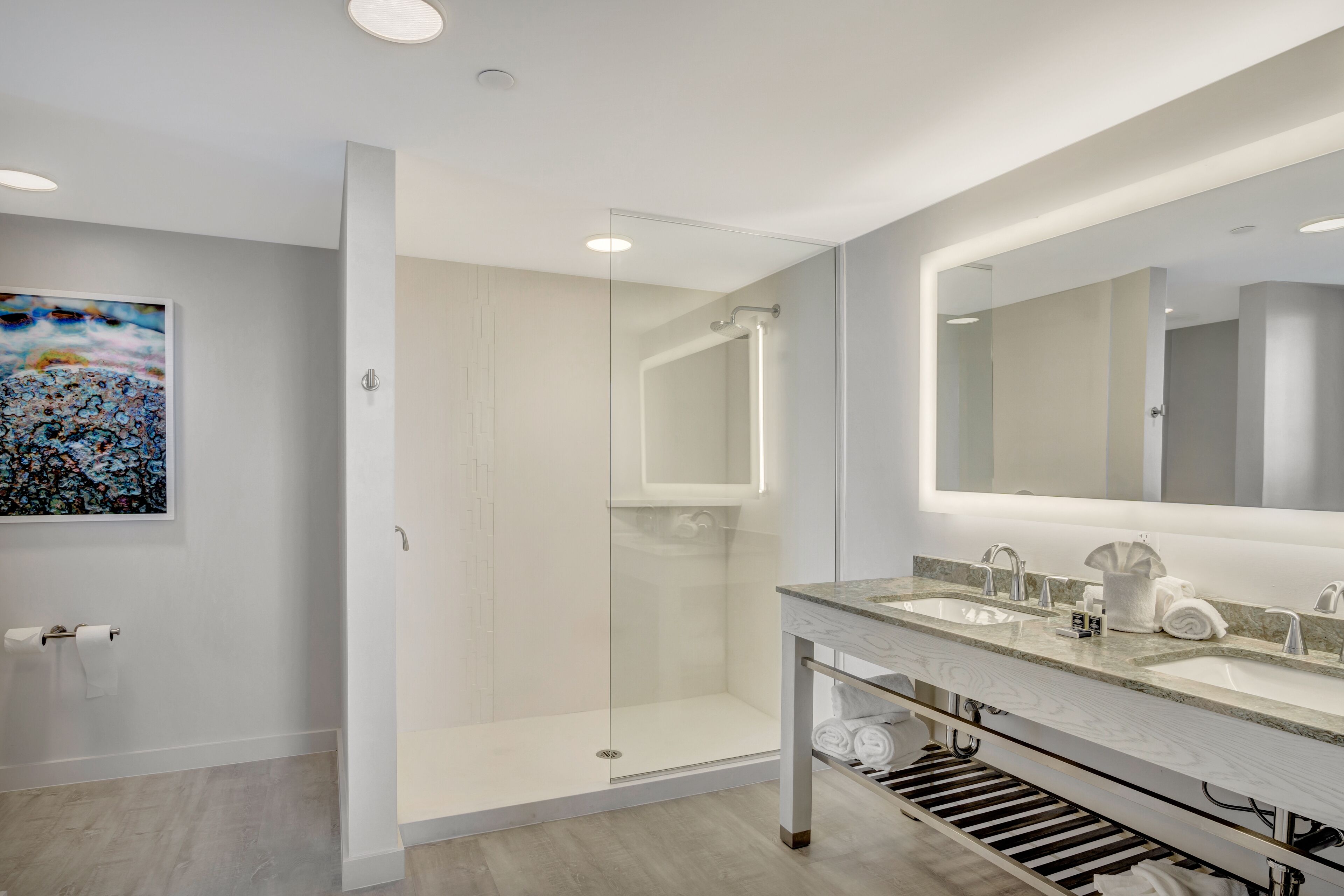Une salle de bain moderne avec une douche à parois de verre, un grand miroir et un plan de toilette en marbre.