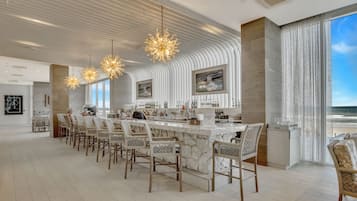 Een moderne bar met een lange toonbank, verschillende barkrukken en hanglampen.