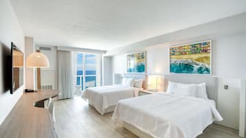 Una habitación de hotel con dos camas, un escritorio, un televisor y obras de arte en las paredes.