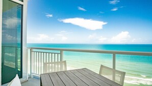 A balcony with a view of the ocean, a wooden table, and white chairs. - Daytona Grande Oceanfront Resort (Daytona Beach)