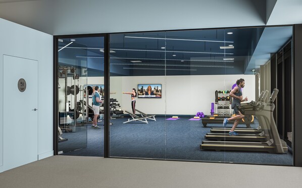 A gym with exercise equipment, a television, and a change room.