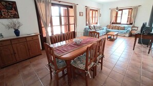 Un área de comedor con una mesa y sillas de madera, un sofá y un televisor en una sala de estar.