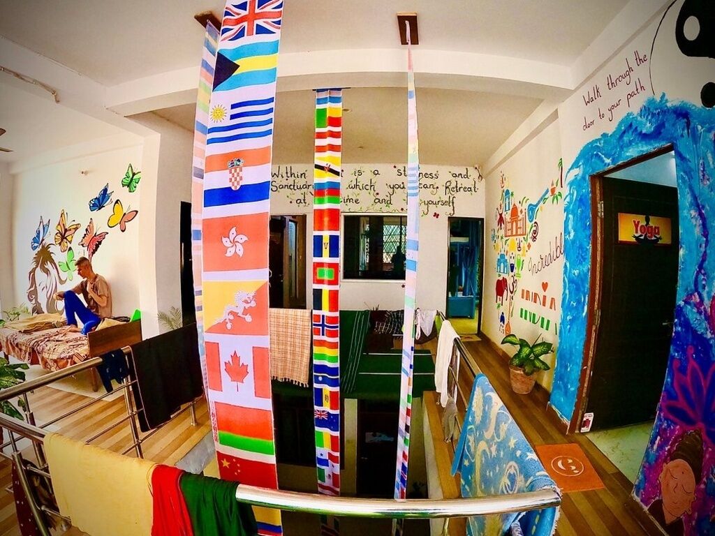 A hotel lobby with a central column featuring international flags, a staircase, and a yoga room entrance.
