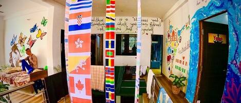 A hotel lobby with a central column featuring international flags, a staircase, and a yoga room entrance.