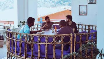 A round table with four people seated, surrounded by a wicker partition with purple cushions.