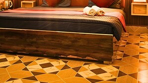 A bedroom with a large bed, wooden paneling, a tiled floor, and a ceiling fan. -  Skyard Hostel Rishikesh (Laxman Jhula) (Yamkeshwar)