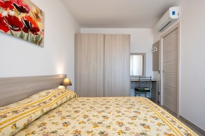 Une chambre à coucher comprenant un lit, un bureau et un appareil de climatisation.