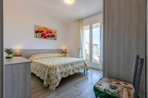 Un dormitorio con una cama, lámparas de noche, un cuadro y vistas por la ventana.