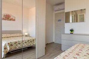 Une chambre à coucher comprenant un lit, une table de chevet, une commode, un miroir et un élément décoratif mural.