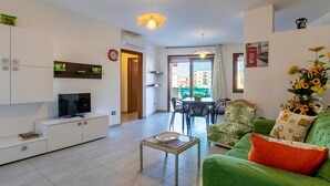 Ein modernes Wohnzimmer mit Fernseher, Sofa und Essbereich.
