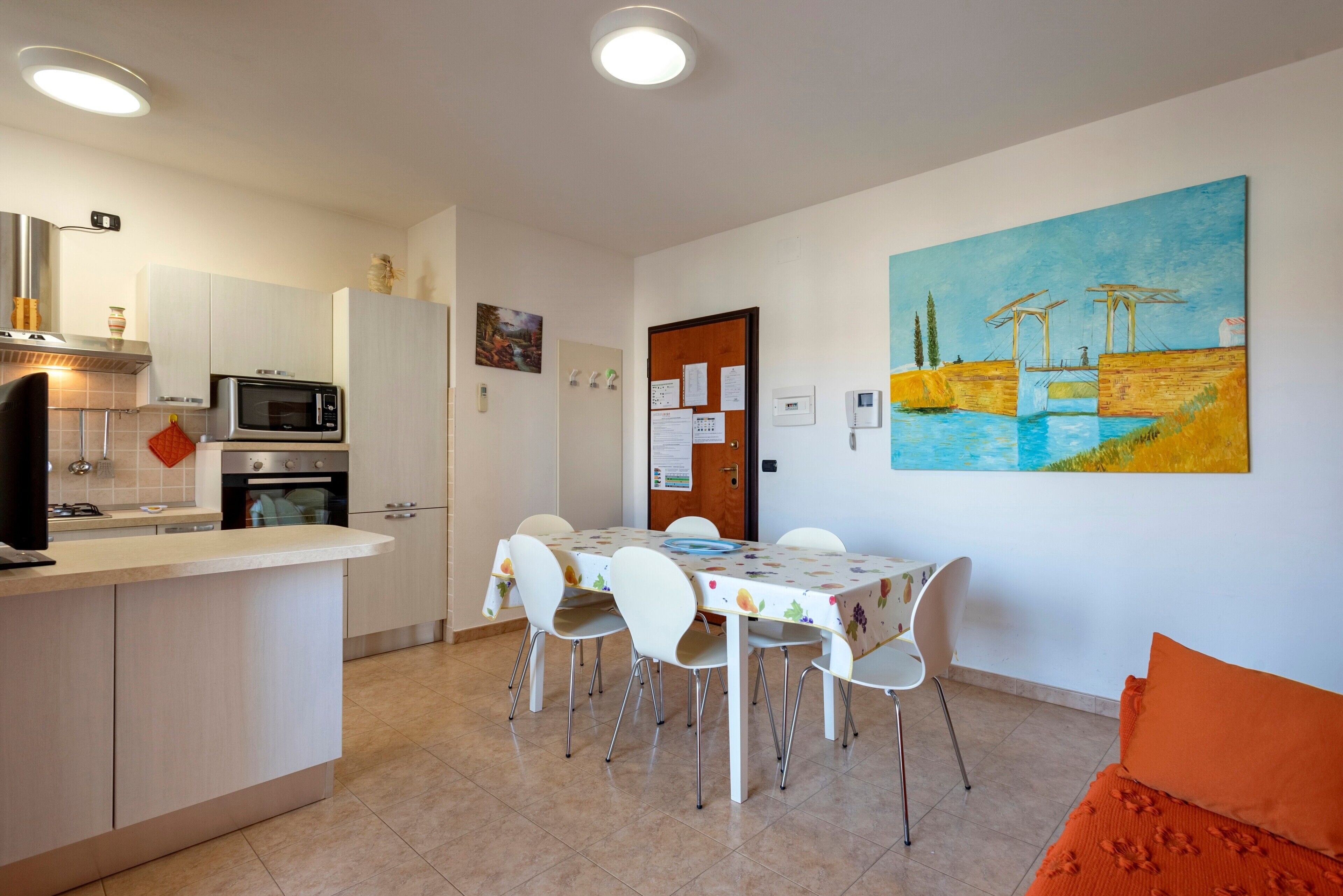 A modern kitchen with a dining area, white cabinets, a microwave, and a painting on the wall.