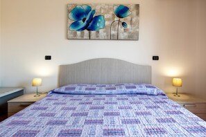 Una camera da letto con un letto, due lampade da comodino, un'opera d'arte appesa al muro e una testiera.