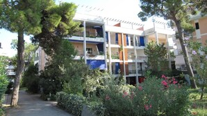 A multi-story hotel with balconies, surrounded by trees and greenery. - Seaview flat with unforgettable terrace (Grado Pineta)