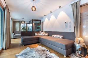 A modern living room with a sectional sofa, a large rug, and a unique wall-mounted light fixture.
