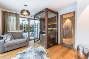 Ein modernes Wohnzimmer mit einer Couch, einer Glastür, die auf einen Balkon führt, und einer Holzkabine.