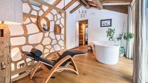 A modern interior with a wooden ceiling, a white bathtub, and a wooden partition with cut-out patterns.