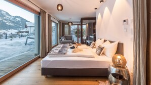 A modern bedroom with a large bed, a view of a snowy landscape, and a wooden floor.