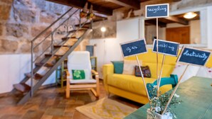 A cozy room with a staircase, a yellow sofa, and signs indicating recycling, gas, parking, and electricity. - TOPAZ in OLD TOWN!  Romantic  near the sea! Alghero smart country style! Wi-Fi (Alghero)