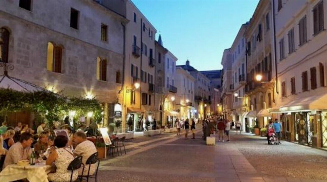 Una strada con edifici, posti a sedere all'aperto e persone.