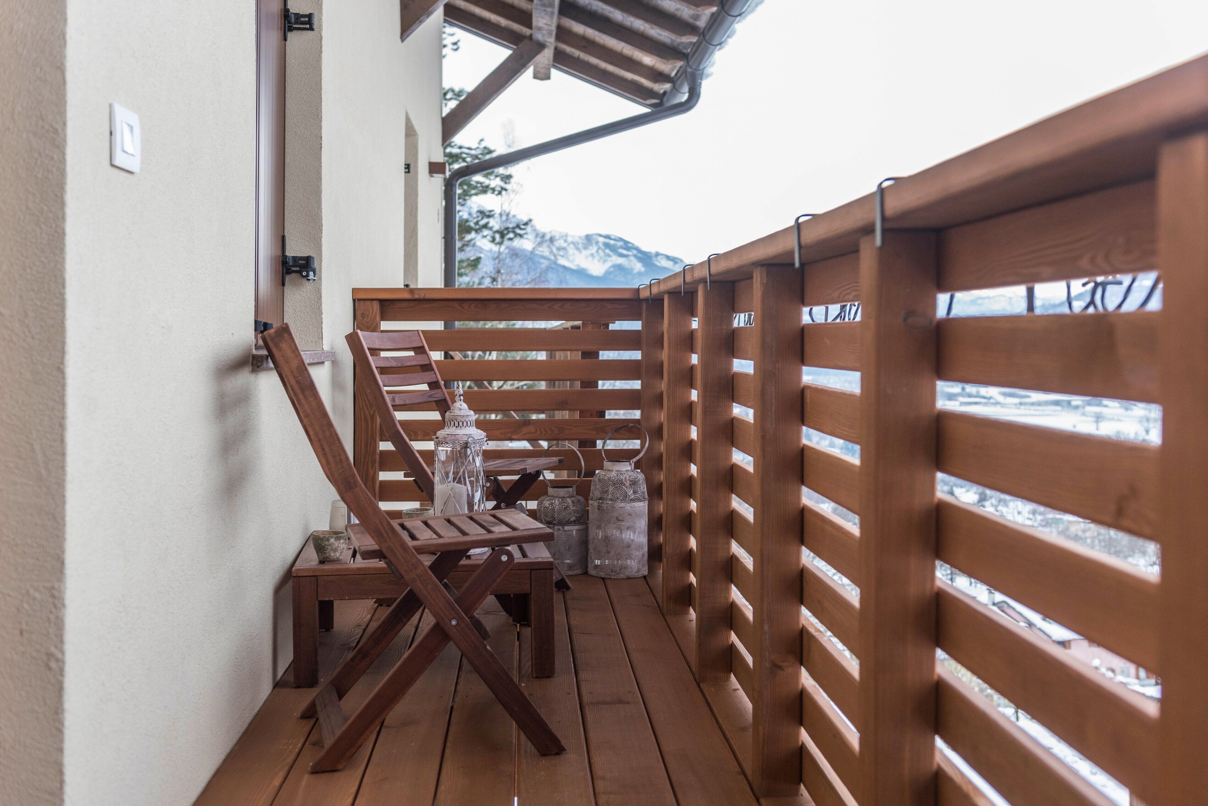 A wooden deck with a table and chairs, a lantern, and metal containers.