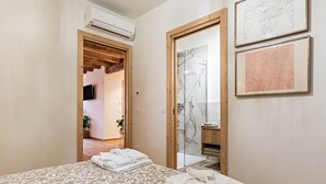 Habitación de hotel con cama, toallas, ducha y cuadros en la pared.