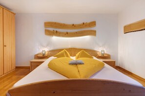 A bedroom with a wooden headboard, a bed with yellow pillows, bedside lamps, and a wooden wardrobe.