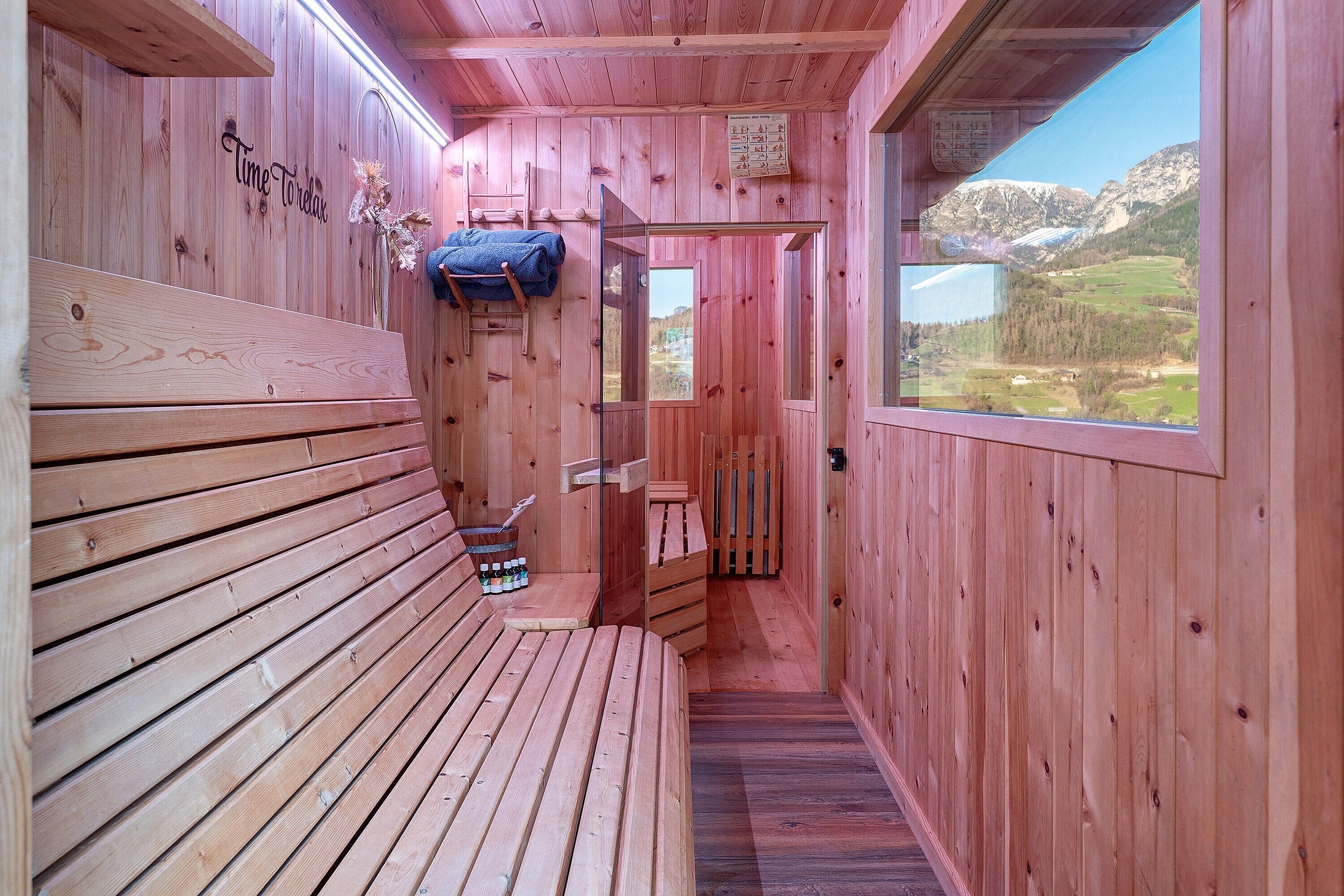 A wooden cabin with a bench, a ladder, and a view of mountains.