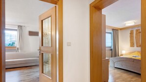 Une pièce avec un lit, une fenêtre avec des rideaux et un plancher en bois.