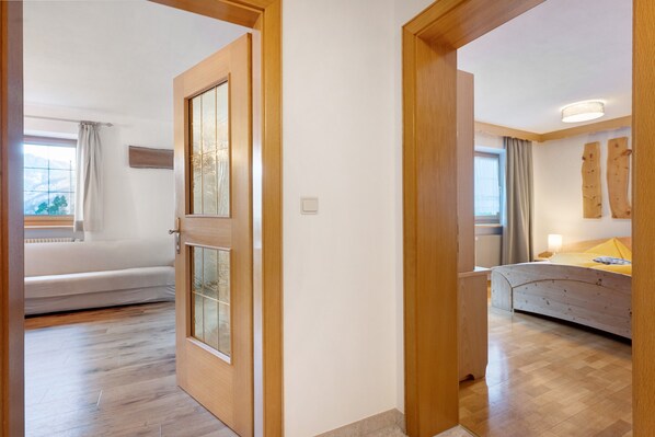 Une pièce avec un lit, une fenêtre avec des rideaux et un plancher en bois.