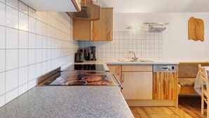 Una cocina con estufa, lavavajillas y armarios de madera.