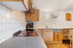 Une cuisine équipée d’une cuisinière, d’un lave-vaisselle et de meubles de rangement en bois.