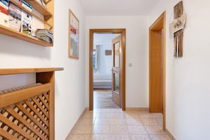 A hallway with a wooden door, a wall-mounted shelf with magazines, and a decorative piece.