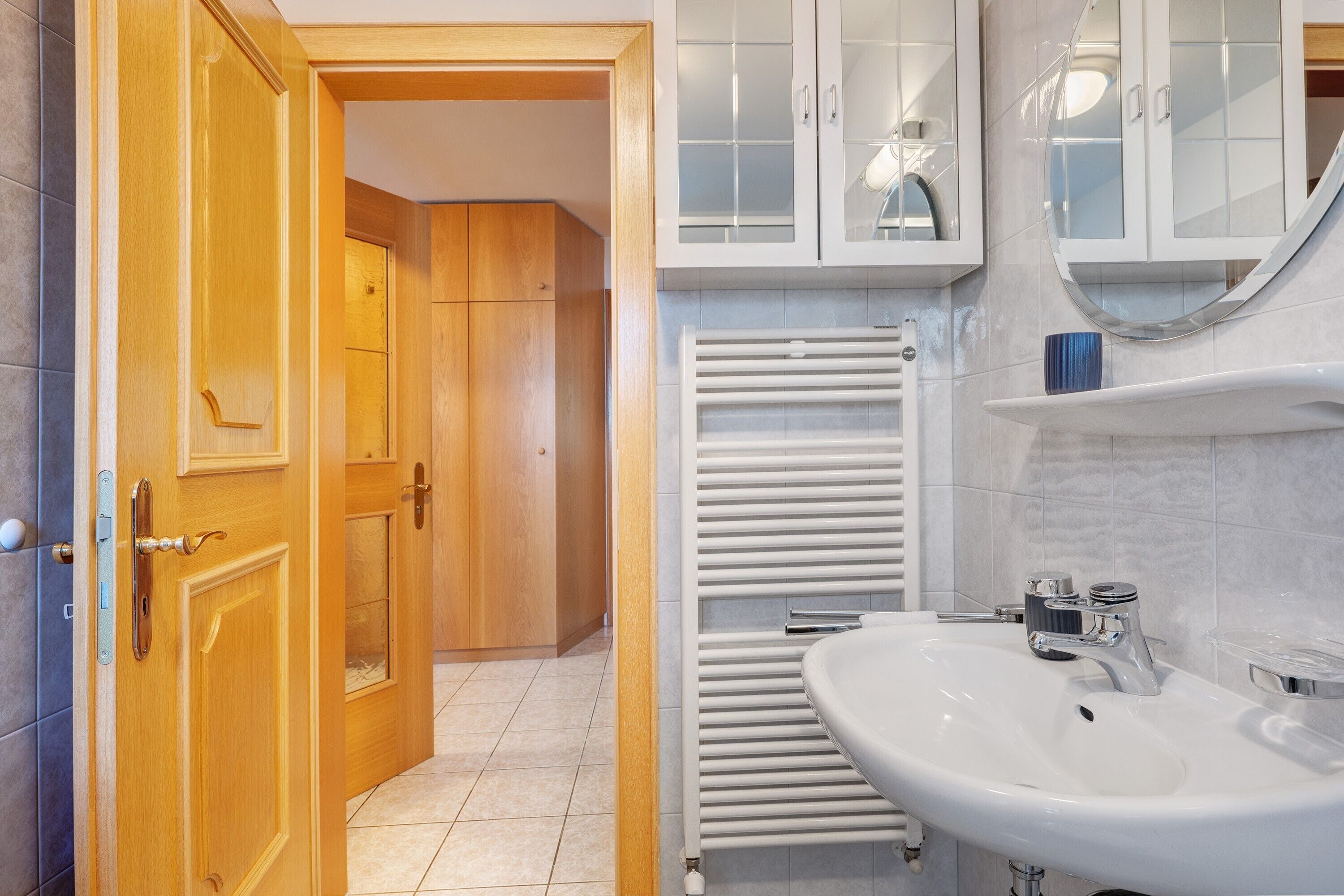 Un baño con lavamanos blanco, toallero y armarios de madera.