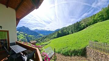 Eine Terrasse mit Blick auf einen grünen Hügel und Berge.