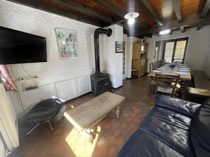 A cozy living area with a fireplace, a sofa, a wooden table, and a television mounted on the wall.